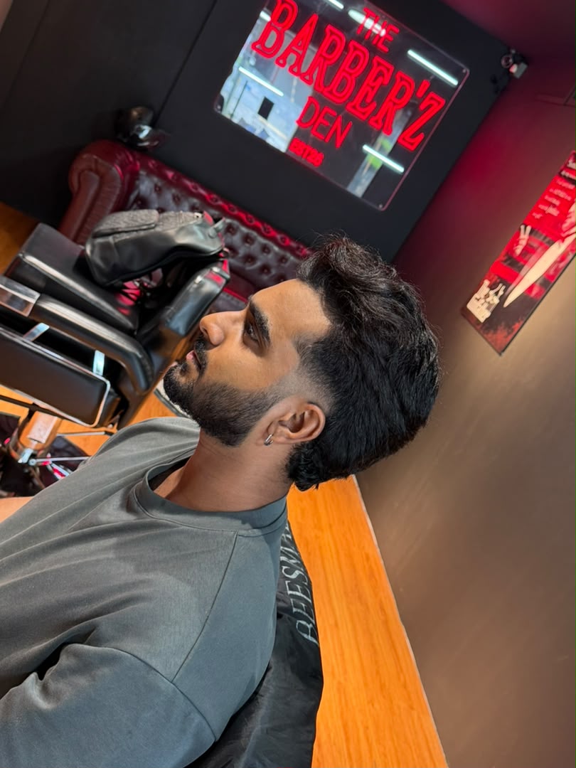 Finished beard and taper haircut with The Barber'Z Den neon sign behind the customer